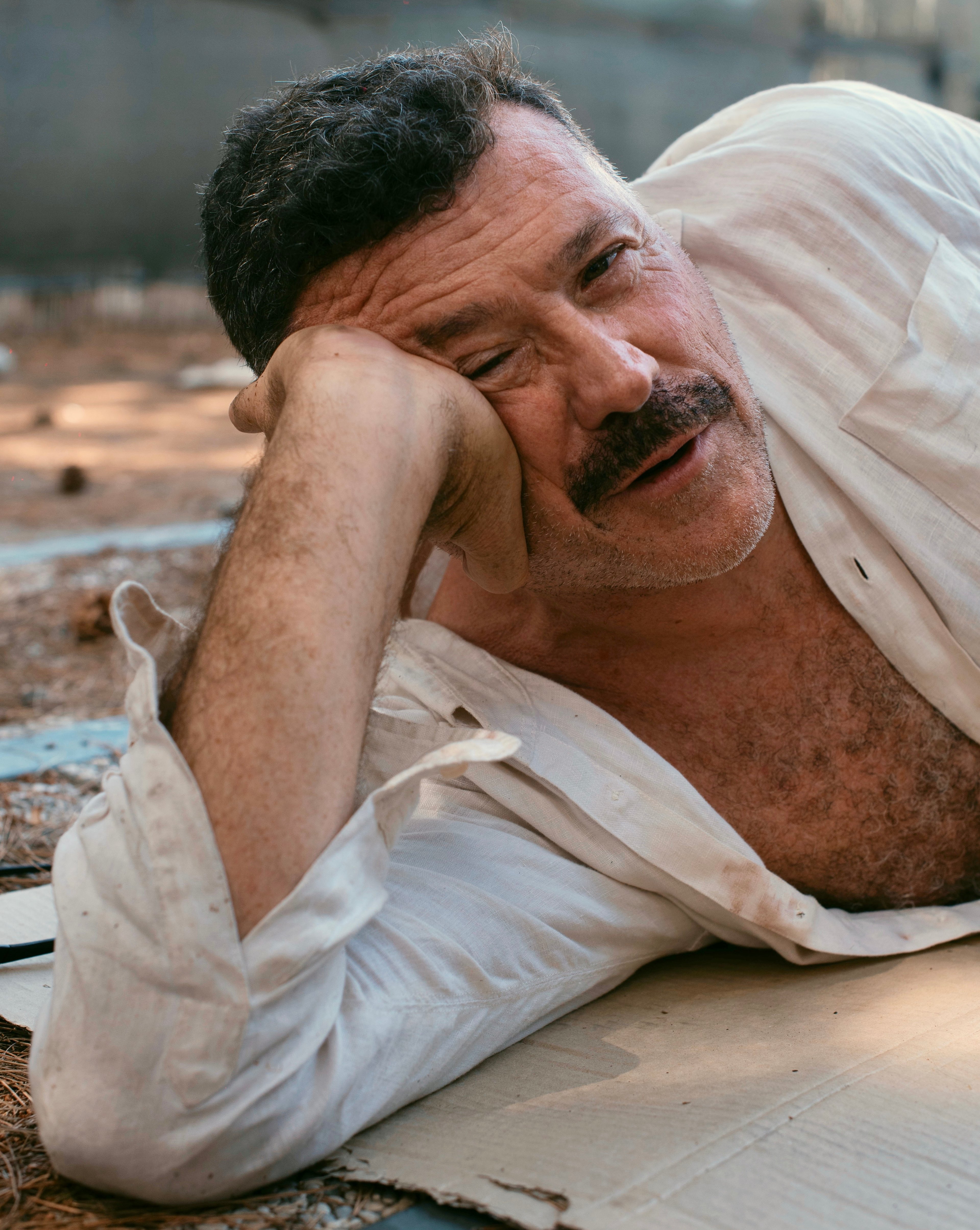 Carlo Antonelli reclinato per terra su un braccio, con una camicia bianca.